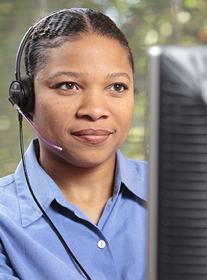 Woman at computer wearing telephone headset.
