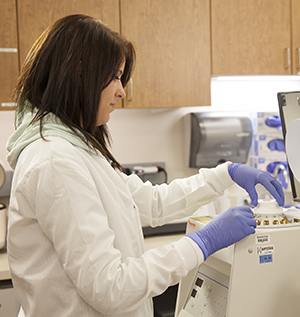 Técnica de laboratorio con equipo de laboratorio y muestras de sangre.